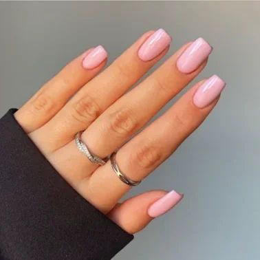 Gros plan d'une main présentant des ongles élégants sur une base rose avec un motif léopard noir sur un ongle et une finition nude mate sur les autres avec une pointe française noire.