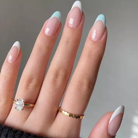 Une image d'une main avec de longs ongles en forme d'amande magnifiquement manucurés présentant de délicats motifs de marguerites avec des pétales blancs et un centre jaune sur deux ongles et une couleur jaune unie sur le reste.